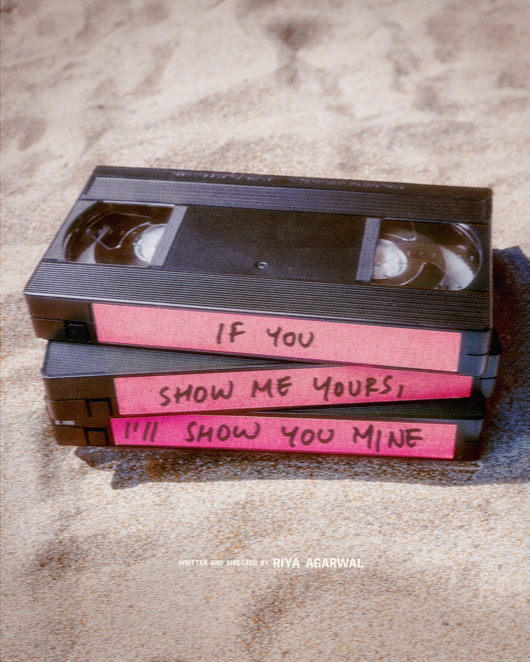 If You Show Me Yours I'll Show You Mine — poster: three VHS tapes stacked on sand, hand-labeled with the film's title