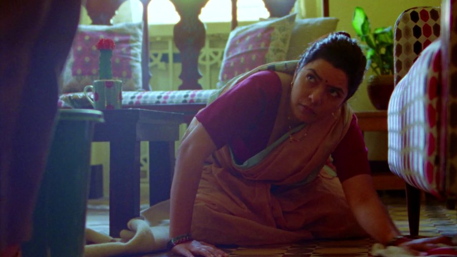 Sunday Matinee — still: a woman in a sari pauses while cleaning the floor, looking up warily